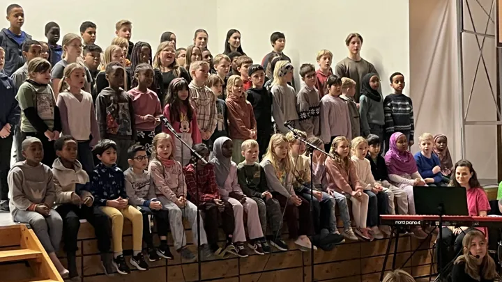 Barn som står på en scene og synger