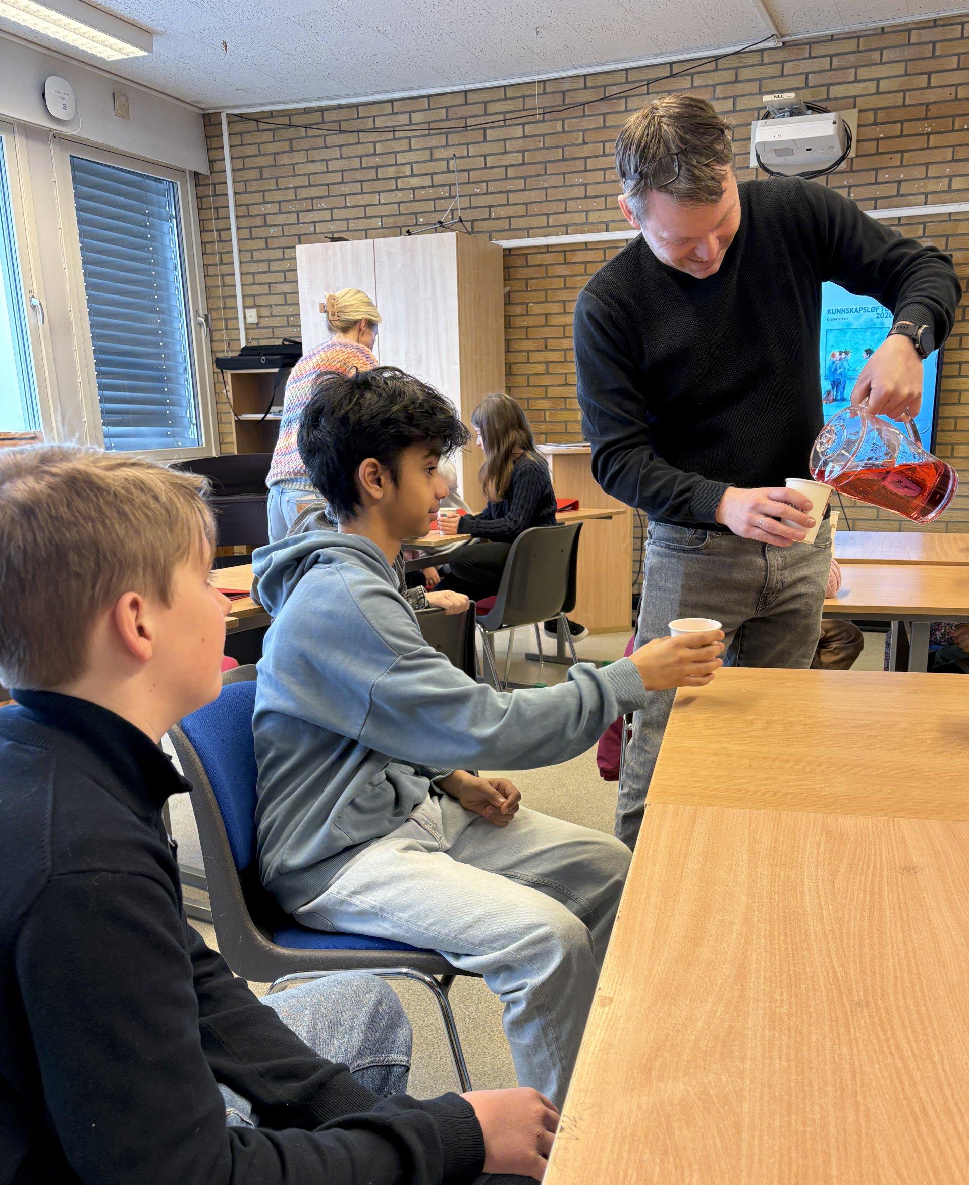 Mann som serverer saft til barn.